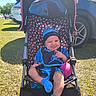 Nael joined the competition — help win amazing prizes! baby, blue_clothing, car, child, grass, happy, hat, infant, outdoor, parking_lot, people, polka_dot, seatbelt, shade, smile, socks, stroller, sunlight, toy, wheel