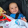 Nael is registered to the contest to win money with this photo: baby, blanket, blue_clothing, child, closeup, comfort, cute, expression, face, happy, head, indoors, infant, person, plush_toy, safety_harness, seated, smiling, stroller, toy