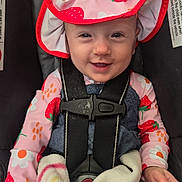 Mckenzie is registered to the contest to win money with this photo: baby, child, car_seat, hat, strawberry, smile, blanket, clothing, safety_harness, cute, infant, person, seatbelt, apparel, headwear, young_child, happy, indoors, portrait, colorful
