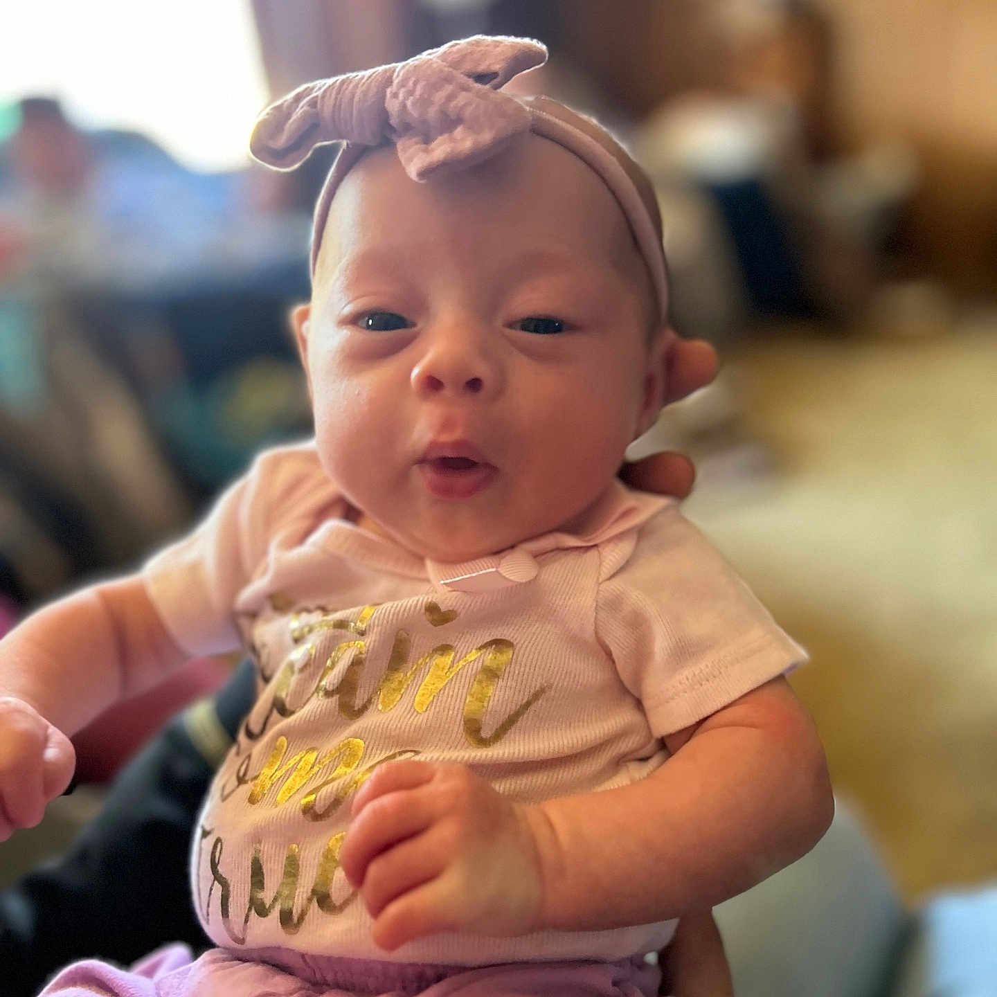 Nova is registered to the contest to win money with this photo: baby, bodypart, bonnet, clothing, dress, face, finger, frown, hand, hat, head, newborn, pants, person, photography, portrait, sad, sitting, t_shirt, wrist