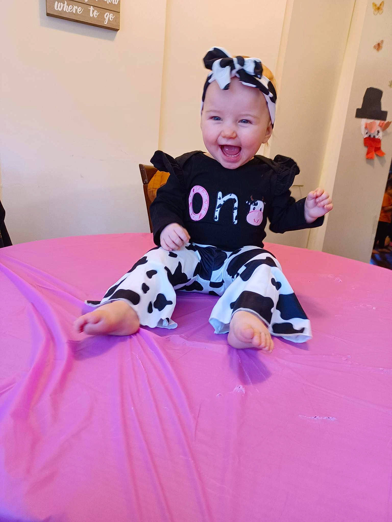 Allison is registered to the contest to win money with this photo: baby, baby_toddler_clothing, costume, floor, flooring, fun, happy, hat, headwear, human_leg, linens, magenta, pattern, person, pink, play, purple, sitting, sleeve, smile