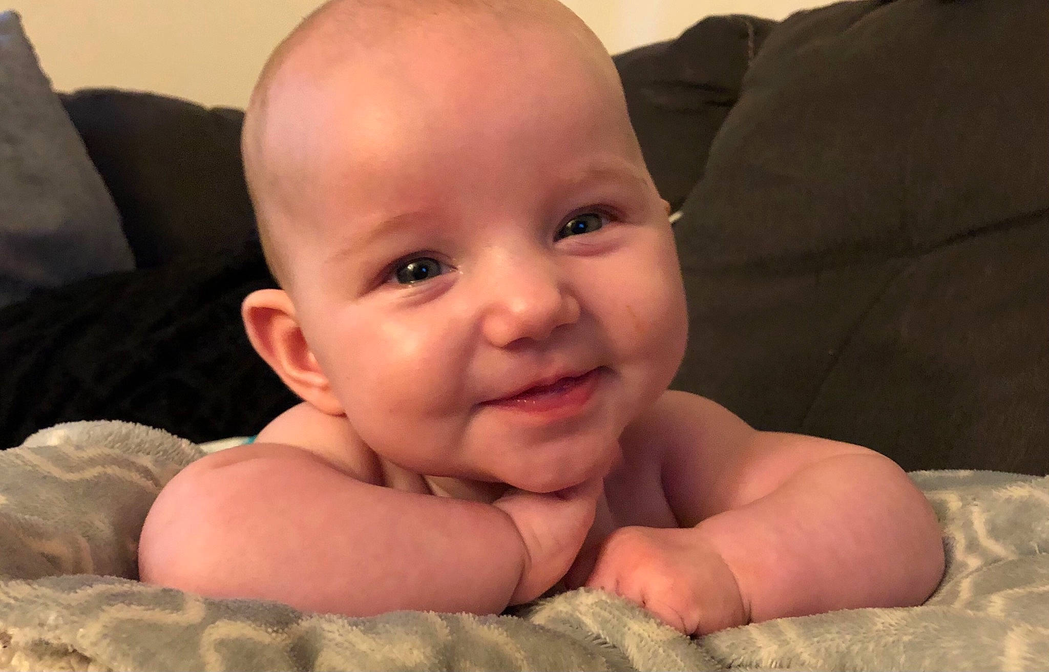 Allison is registered to the contest to win money with this photo: baby, baby_toddler_clothing, cheek, chest, comfort, eye, finger, foot, gesture, happy, human_body, iris, joy, linens, lip, nail, nose, person, sitting, smile