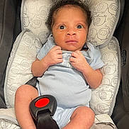 Avery joined the competition — help win amazing prizes! baby, newborn, infant, car_seat, onesie, clothing, curly_hair, face, eyes, hands, legs, foot, seatbelt, pattern, fabric, child, person, cute, indoor, portrait