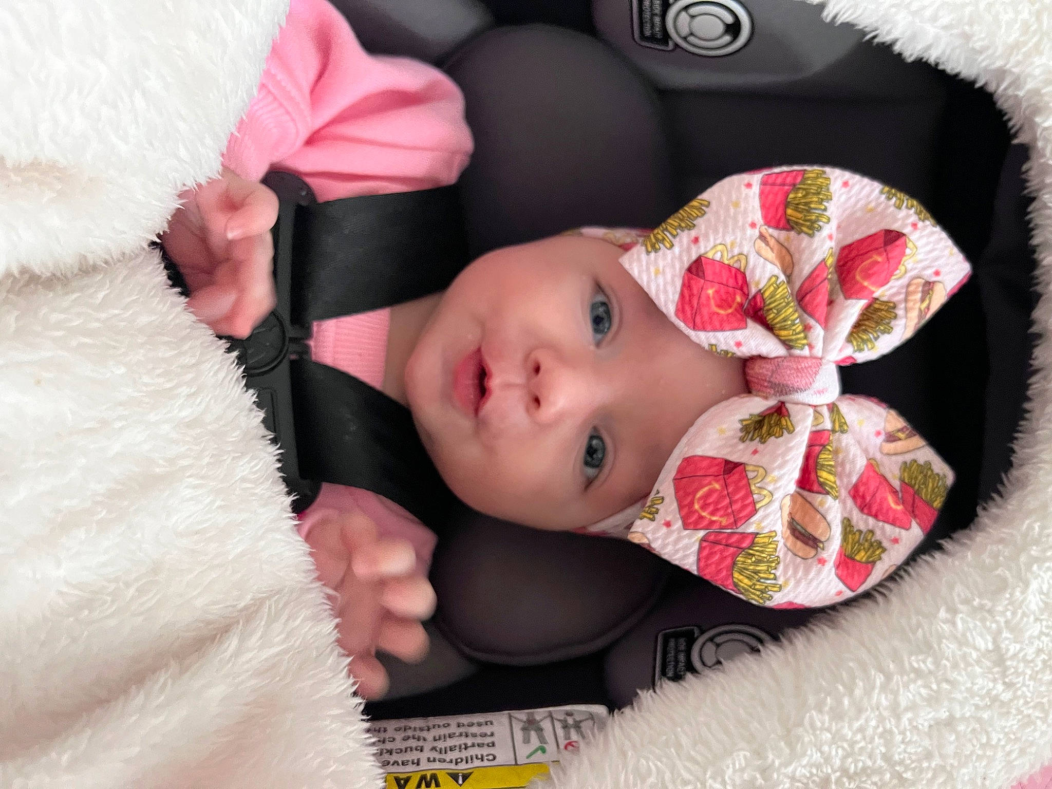 Lorelai is registered to the contest to win money with this photo: baby, baby_products, baby_toddler_clothing, car_seat, carmine, child, comfort, eyelash, fashion_accessory, fur, headgear, headwear, linens, pattern, person, pink, plaid, skin, sleeve, toddler