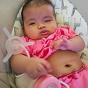 Liliana joined the competition — help win amazing prizes! baby, infant, pink_clothing, bottle, feeding, face, hand, cushion, pattern, giraffe_print, sitting, indoors, cute, child, person, skin, expression, milk, relaxing, young
