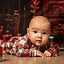 Elyo participe au concours pour gagner de l'argent avec cette photo : baby, infant, plaid_clothing, floor, portrait, child, cute, indoor, wooden_floor, face, eyes, hands, crawling, young, warm_lighting, background_blur, red, white, cozy, expression