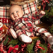 Elyo participe au concours pour gagner de l'argent avec cette photo : baby, child, plaid_pajamas, smiling, face, pillow, christmas_decorations, candy_cane, gingerbread_man, green_garland, red_bow, holiday, festive, indoor, cozy, happy, cute, sock, wooden_table, celebration