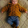 baby, boots, child, clothing, cozy, cute, expression, face, footwear, hat, indoor, infant, jacket, lying_down, mattress, pants, pattern, portrait, small_hands, warm_clothing