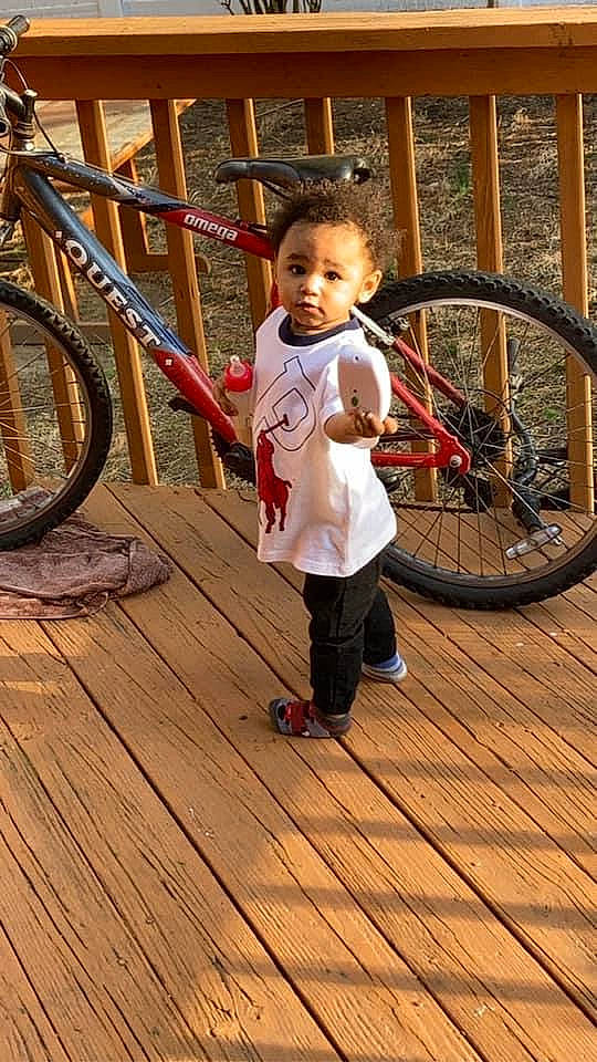 Jayceon is registered to the contest to win money with this photo: bicycle, bicycle_fork, bicycle_frame, bicycle_part, bicycle_tire, bicycle_wheel, bicycles_equipment_and_supplies, child, flooring, hardwood, leg, leisure, person, sneakers, spoke, t_shirt, tire, toddler, vehicle, wheel