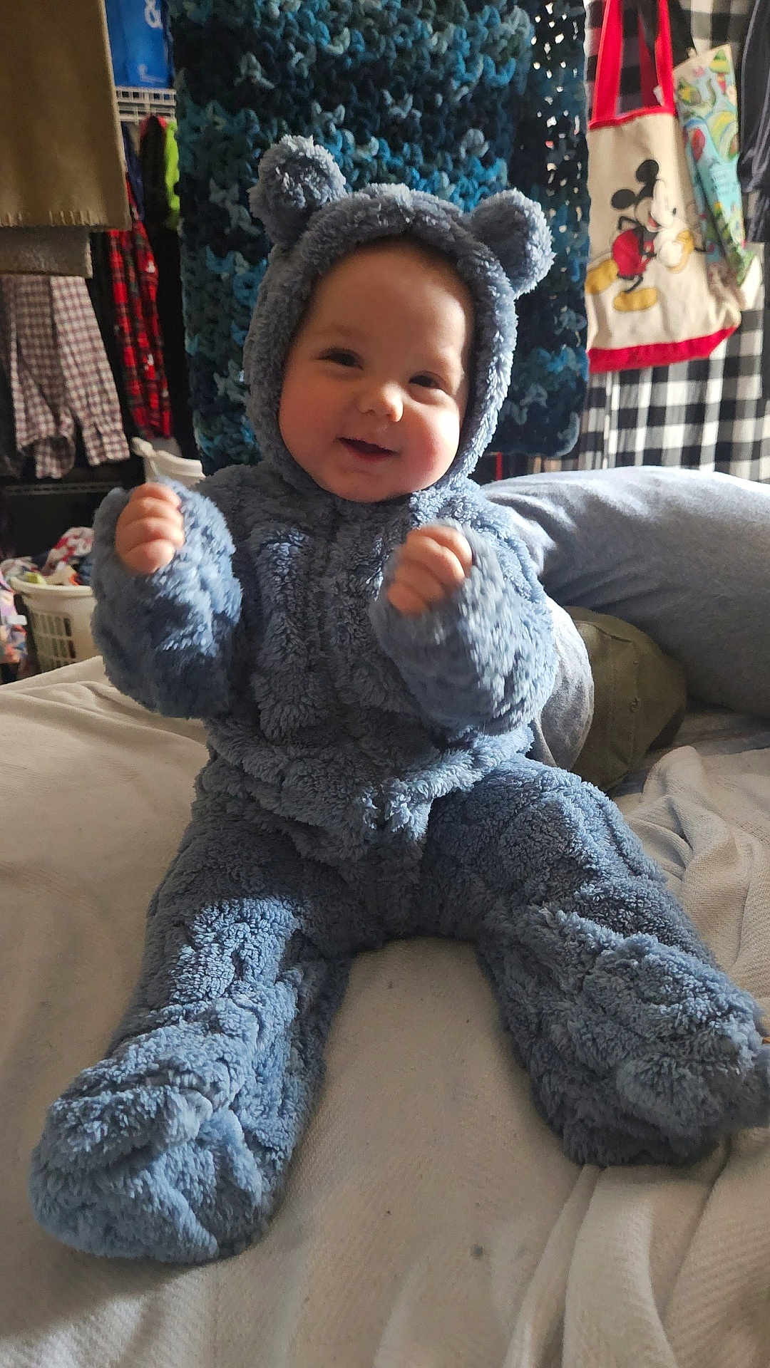 Alakai joined the competition — help win amazing prizes! baby, child, blue_onesie, costume, fluffy, smiling, indoor, bed, blanket, clothing, cute, person, face, happy, furniture, plush, sitting, raised_hands, room, cozy