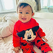 Ngaugin is registered to the contest to win money with this photo: baby, bed, child, cozy, cute, happy, hat, indoor, infant, knitted_hat, mickey_mouse, person, playful, portrait, red_clothing, sitting, smiling, toddler, warm_clothing, young_child
