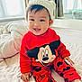 baby, bed, child, cozy, cute, happy, hat, indoor, infant, knitted_hat, mickey_mouse, person, playful, portrait, red_clothing, sitting, smiling, toddler, warm_clothing, young_child