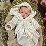 baby, infant, newborn, white_robe, hood, tinsel, christmas, holiday, festive, blanket, plush_bed, cozy, portrait, blue_eyes, gaze, hands, soft_texture, indoor, cute, smile