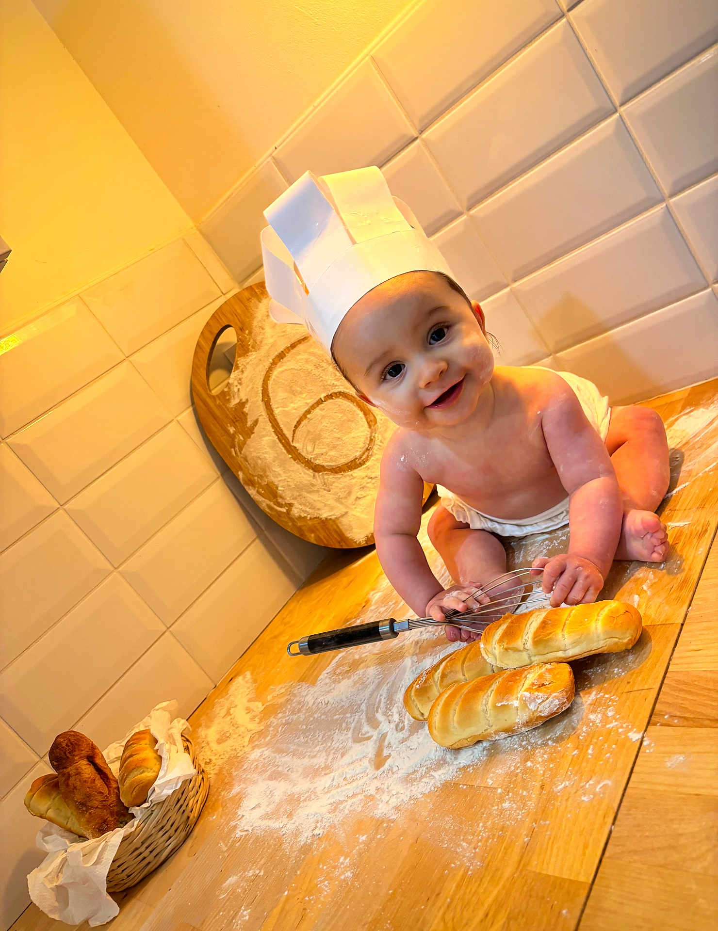 Zayn a rejoint le concours — aidez-le/la à gagner de superbes lots ! baby, chef_hat, bread, whisk, kitchen, flour, cutting_board, basket, smiling, cooking, wooden_counter, tile_wall, diaper, playful, baking, infant, dough, food, cooking_utensil, happy