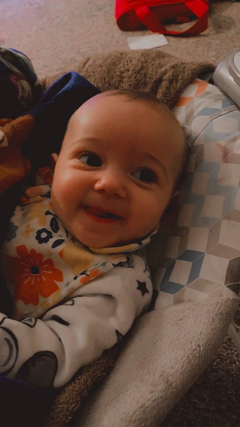 Clara joined the competition — help win amazing prizes! baby, baby_toddler_clothing, brown, cheek, child, comfort, eye, facial_expression, fun, happy, head, iris, linens, mouth, nose, person, sitting, skin, smile, textile