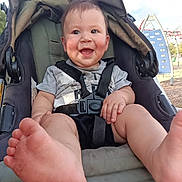 Christian is registered to the contest to win money with this photo: baby, child, infant, smiling, happy, stroller, outdoor, playground, playground_equipment, blue_sky, clouds, portrait, face, eyes, feet, barefoot, harness, seated, park, daylight