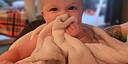 Willow joined the competition — help win amazing prizes! baby, blanket, infant, face, hand, skin, indoor, person, soft_texture, cuddle, cute, child, smile, happy, cozy, portrait, furniture, tattoo, blurred_background, family