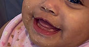 Joseline is registered to the contest to win money with this photo: baby, blanket, caregiver, child, close_up, eyes, face, food, happy, heart_pattern, indoor, infant, messy_face, open_mouth, pink_clothing, portrait, seated, smiling, tongue, wood_floor