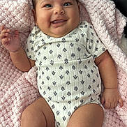 Samira is registered to the contest to win money with this photo: baby, black_socks, blanket, child, comfort, cozy, cute, face, hand, happy, indoors, infant, legs, lying_down, onesie, patterned_clothing, plush_toy, skin, smiling, soft_texture