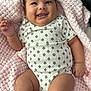 baby, black_socks, blanket, child, comfort, cozy, cute, face, hand, happy, indoors, infant, legs, lying_down, onesie, patterned_clothing, plush_toy, skin, smiling, soft_texture