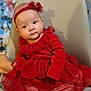 baby, child, red_dress, headband, christmas_tree, ornaments, chair, holiday, festive, smiling, cute, indoors, decorations, celebration, person, footwear, sitting, soft_lighting, happy, portrait