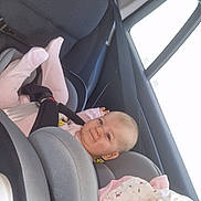 Lëhyna a rejoint le concours — aidez-le/la à gagner de superbes lots ! baby, car_seat, child, infant, pink_clothing, stuffed_animal, car_interior, seatbelt, window, headrest, smiling, safety, transportation, toddler, cute, comfort, child_safety, seat, happy, young_child