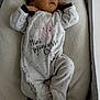 baby, newborn, sleeping, onesie, star_pattern, text_on_clothing, infant, cozy, soft_texture, cushion, resting, peaceful, cute, child, indoor, portrait, clothing, babywear, small_hands, closed_eyes