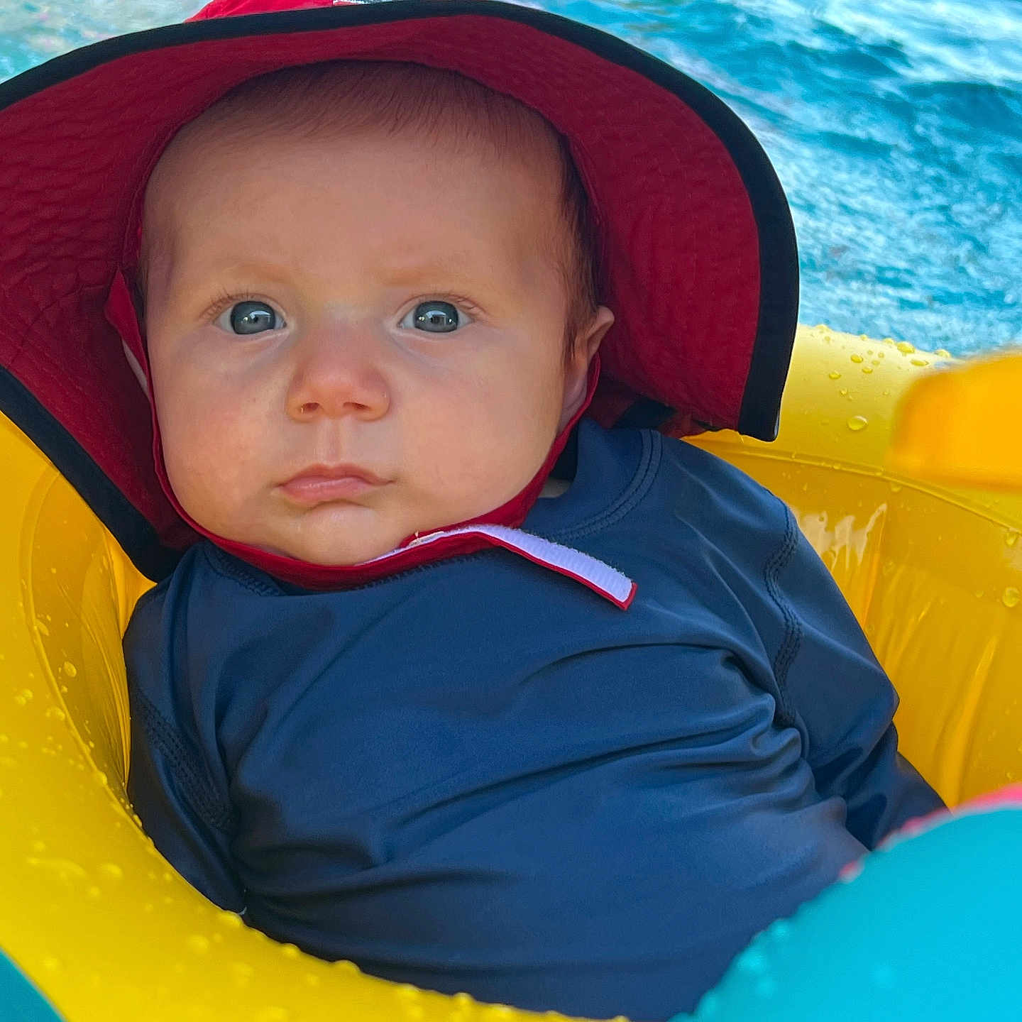 Boden is registered to the contest to win money with this photo: baby, cap, clothing, coat, face, hat, head, inflatable, lifejacket, outdoors, person, photography, pool, portrait, summer, sunhat, swimmingpool, toy, vest, water