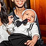 Raphaël participe au concours pour gagner de l'argent avec cette photo : adult, baby, black_and_white, bow_tie, celebration, child, closeup, clothing, cute, family, happy, headwear, holding, indoor, people, person, portrait, smile, toddler, wood_paneling
