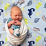 Luke is registered to the contest to win money with this photo: newborn, baby, infant, blanket, swaddled, sock, dinosaur_pattern, sleeping, cute, peaceful, soft, blue, white, child, portrait, indoors, small, wrapped, infant_clothing, resting