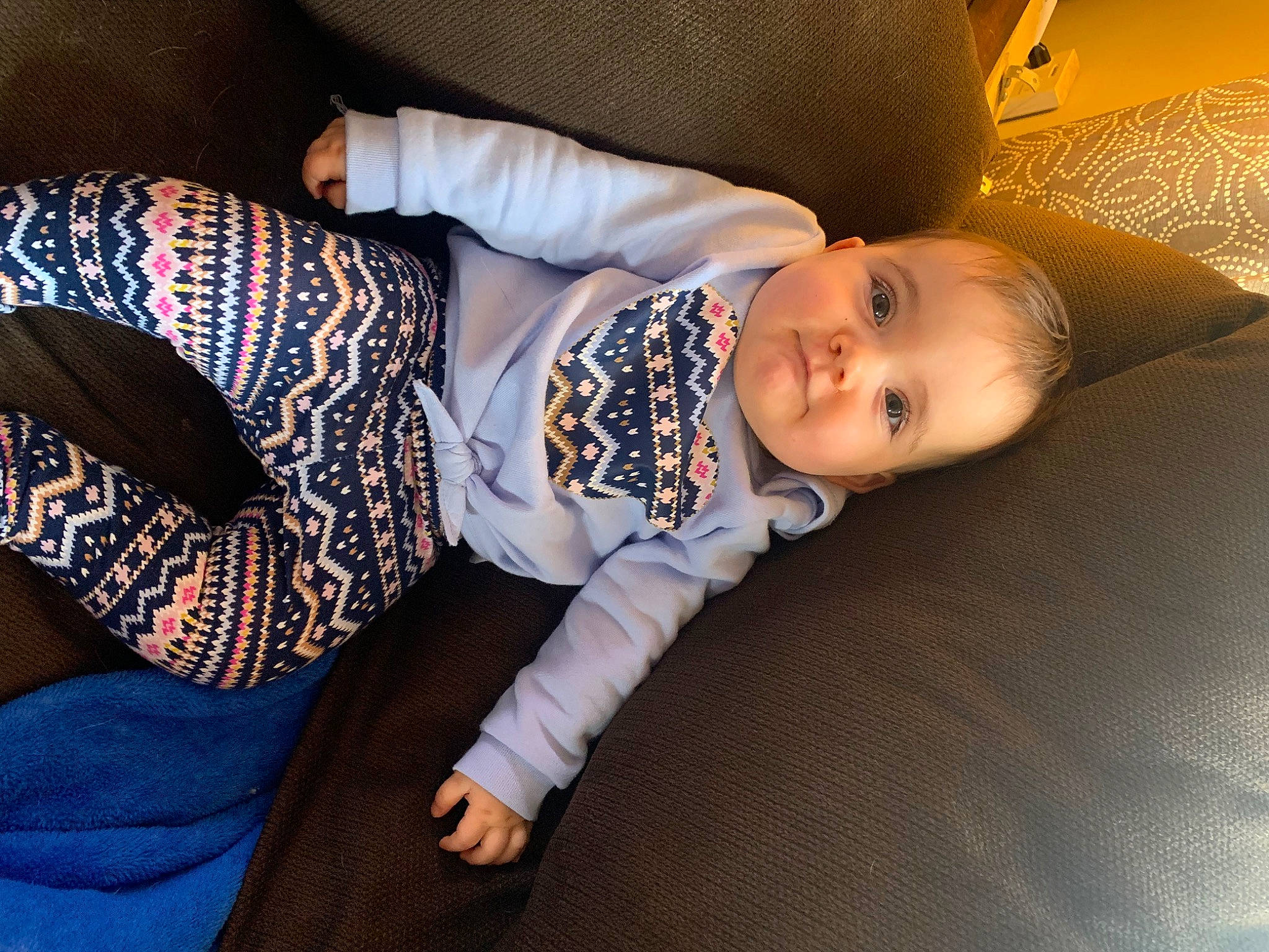Kylee joined the competition — help win amazing prizes! baby, baby_toddler_clothing, cheek, child, comfort, couch, finger, flooring, head, human_leg, knee, linens, pattern, person, sitting, sleeve, smile, sock, thigh, toddler