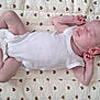 baby, sleeping, infant, onesie, quilt, heart_pattern, peaceful, soft_texture, newborn, skin, lying_down, cute, resting, small_hands, small_feet, bedtime, nap, indoors, cozy, calm