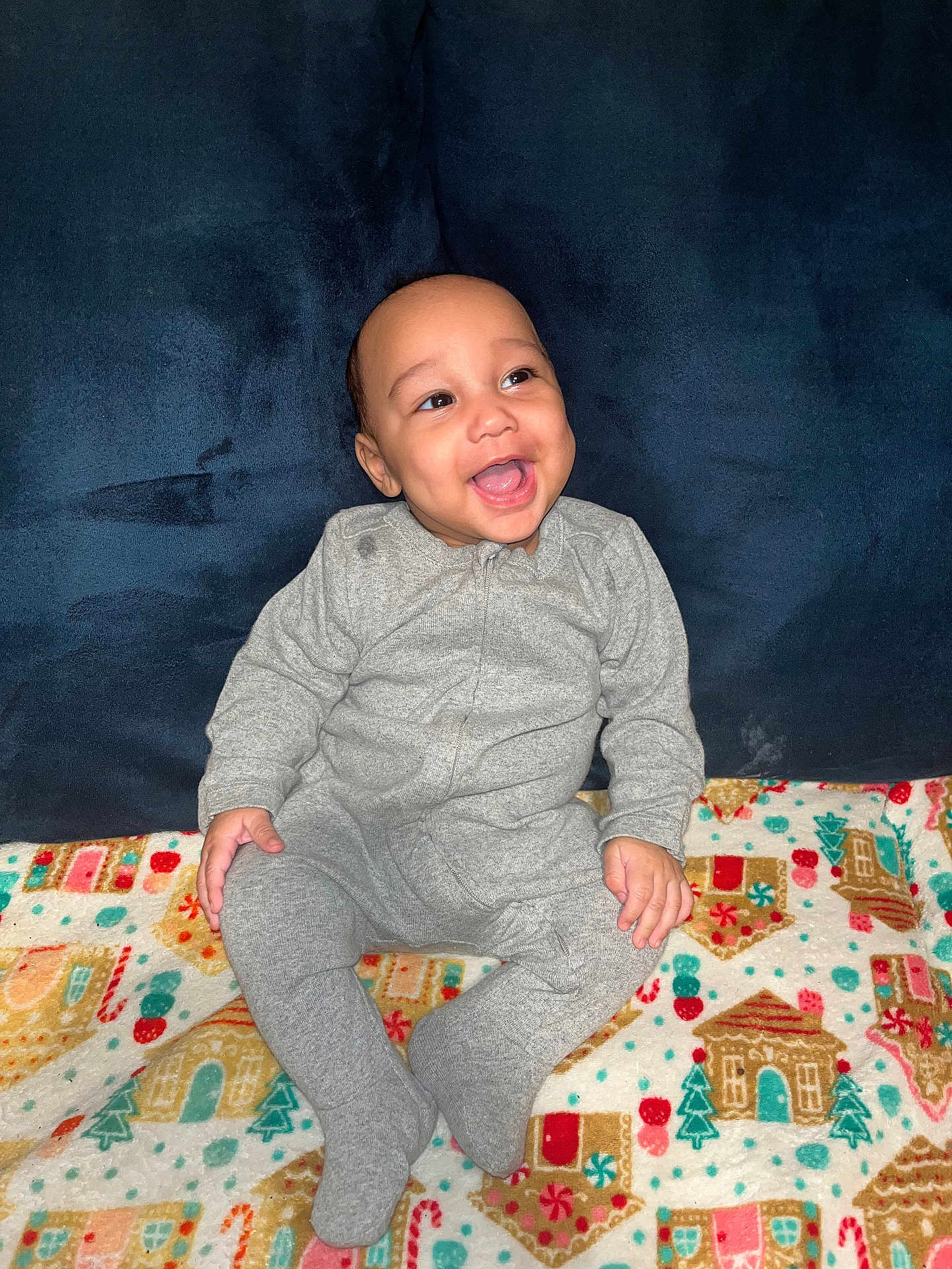 Demuir joined the competition — help win amazing prizes! baby, child, smiling, gray_onesie, blanket, holiday_theme, gingerbread_house, candy_cane, sitting, happy, cute, indoor, portrait, cozy, infant, plush, colorful, clothing, face, joyful
