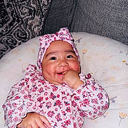 Dayani is registered to the contest to win money with this photo: baby, infant, child, smiling, floral_outfit, pink_clothing, headband, bow, thumb_sucking, portrait, face, eyes, cheeks, sitting, cushion, blanket, sofa, indoor, happy, photography