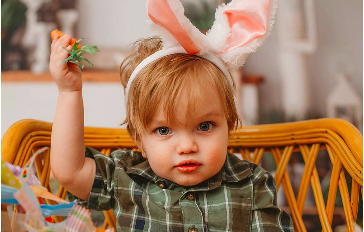 Jensen is registered to the contest to win money with this photo: baby_toddler_clothing, child, ear, event, eyelash, face, fun, green, happy, head, headpiece, holiday, orange, party_supply, people, person, plaid, room, sitting, tartan