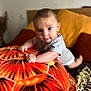baby, infant, pillow, orange, pattern, cushion, bed, blanket, indoors, person, cute, child, smiling, face, eyes, toddler, clothing, soft, comfort, home