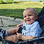 baby, child, smiling, stroller, outdoor, waterfront, grass, pavement, sneakers, black_and_white, happy, cute, person, summer, nature, casual_clothing, sunlight, face, head, legs