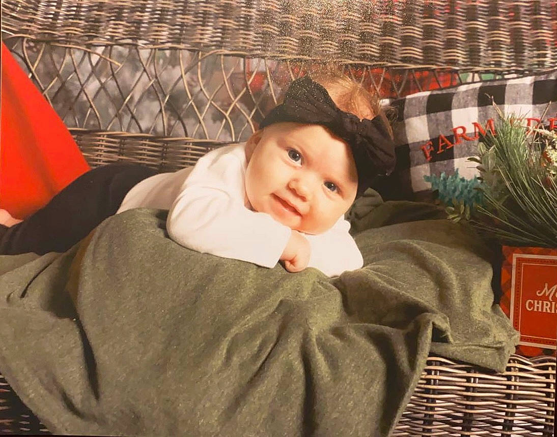 Happy joined the competition — help win amazing prizes! baby, baby_toddler_clothing, child, comfort, couch, fashion_accessory, flower, flower_arranging, fur, headwear, linens, pattern, people, person, plaid, plant, room, sitting, sleeve, smile