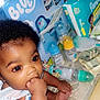 baby, infant, hand, fingers, diapers, baby_bottles, money, table, person, child, curly_hair, cute, indoor, skin, closeup, sitting, holding, bright_eyes, clothing, baby_product