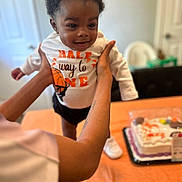 Jakory joined the competition — help win amazing prizes! toddler, child, baby, smiling, person, birthday_cake, cake, shirt, clothing, indoor, table, celebration, hands, face, happy, shorts, white_shoes, adult, arms, party