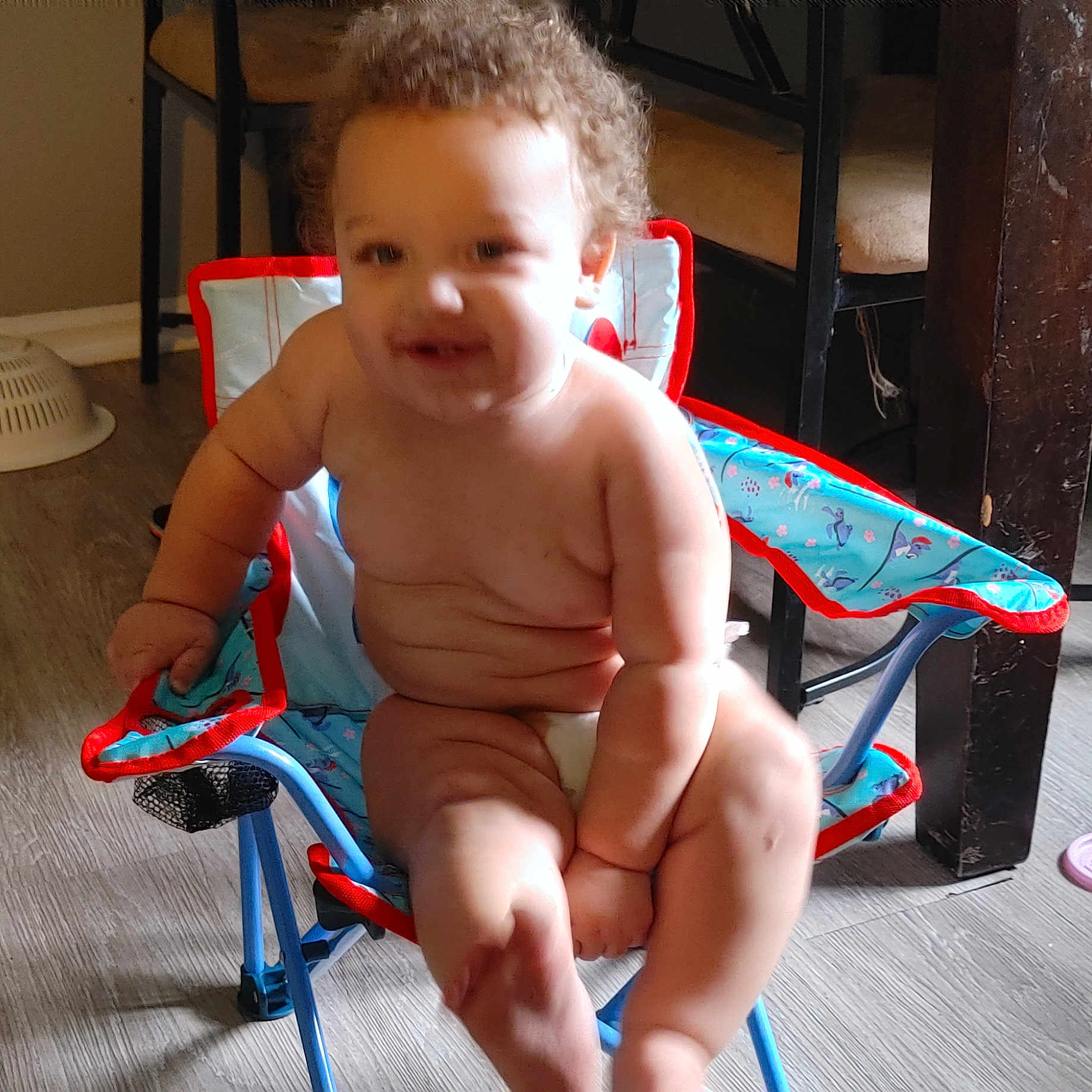 Isiaha joined the competition — help win amazing prizes! arm, baby, chair, child, colander, colorful, curly_hair, cute, diaper, floor, furniture, happy, indoor, legs, person, plump, seat, smiling, table, wooden_floor
