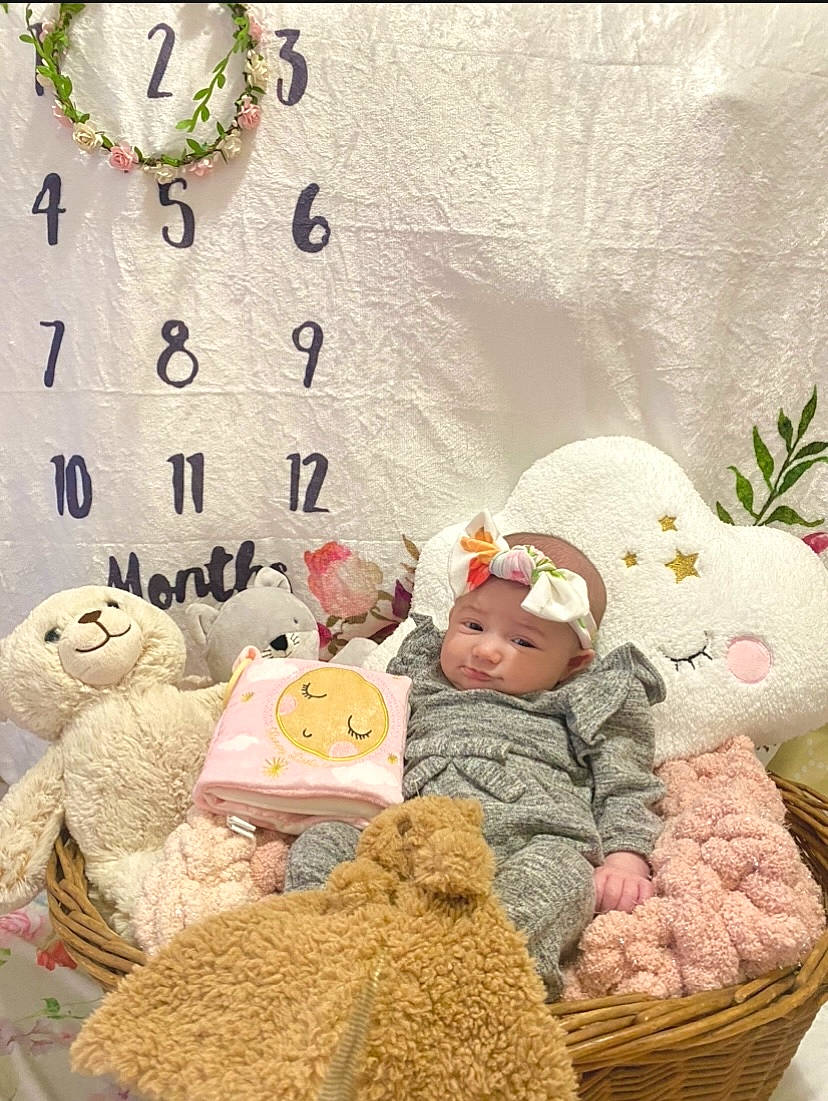 Nova is registered to the contest to win money with this photo: baby, baby_toddler_clothing, cap, child, comfort, fur, hat, headwear, linens, mammal, pattern, person, pink, plush, product, room, stuffed_toy, textile, toddler, toy