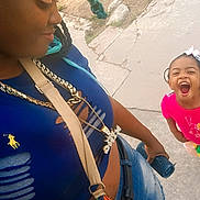 Nevaeh is registered to the contest to win money with this photo: accessories, blue_shirt, braids, casual_clothing, child, concrete, daylight, happy, joy, laughing, outdoor, person, pink_shirt, portrait, side_profile, smile, street, water_bottle, woman, young_girl