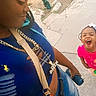 accessories, blue_shirt, braids, casual_clothing, child, concrete, daylight, happy, joy, laughing, outdoor, person, pink_shirt, portrait, side_profile, smile, street, water_bottle, woman, young_girl