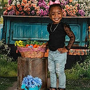 Nevaeh is registered to the contest to win money with this photo: child, girl, smiling, pink_bow, black_top, jeans, sandals, basket, vegetables, wooden_crate, flowers, garden, outdoor, rustic, truck_bed, greenery, portrait, happy, posing, nature
