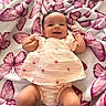 Sariah is registered to the contest to win money with this photo: baby, infant, smiling, blanket, butterfly_pattern, pink, clothing, cute, happy, lying_down, child, soft_texture, indoors, portrait, newborn, small_arms, tiny_fingers, fabric, cozy, relaxed