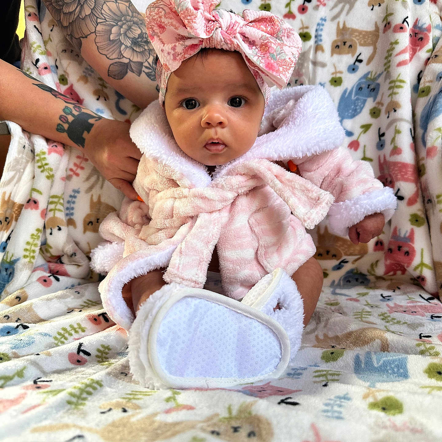 Sariah is registered to the contest to win money with this photo: baby, infant, pink_robes, headband, bow, tattooed_arms, blanket, animal_pattern, cute, sitting, portrait, indoor, soft_texture, colorful, child, young, person, cozy, clothing, adorable