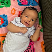 Sariah is registered to the contest to win money with this photo: baby, smiling, infant, blanket, colorful, happy, lying_down, cute, child, person, white_clothing, indoors, soft_texture, playful, face, young, toddler, cozy, cheerful, portrait