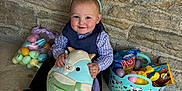 Grayson is registered to the contest to win money with this photo: toddler, child, bunny_ears, stuffed_animal, easter_eggs, basket, candy, toy, stone_wall, bench, smiling, cute, indoors, plush, clothing, headband, happy, sitting, holiday, celebration