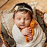 baby, sleeping, infant, wrapped, teddy_bear, knitted_toy, headband, flower, wicker_basket, cozy, cute, peaceful, hands, wooden_floor, blanket, portrait, child, soft_light, indoor, newborn